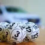 Three white bingo balls with black numbers on them, on a table.