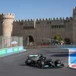 A Mercedes F1 car races around the Baku circuit with the historic city walls in the background.