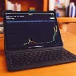 An upwards trending candlestick chart on a laptop screen.