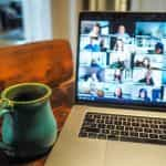 A Macbook displays a group of people on a Zoom call.