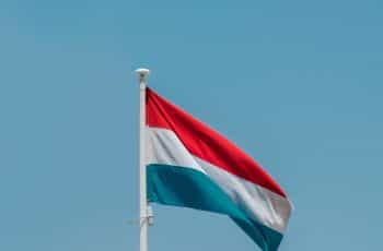 A red, white, and blue flag on a flagpole against a blue sky.