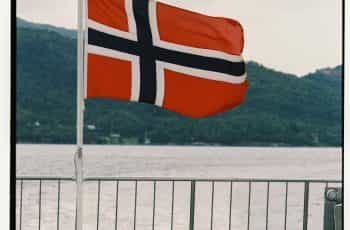 A flag hoisted on a deck near water.