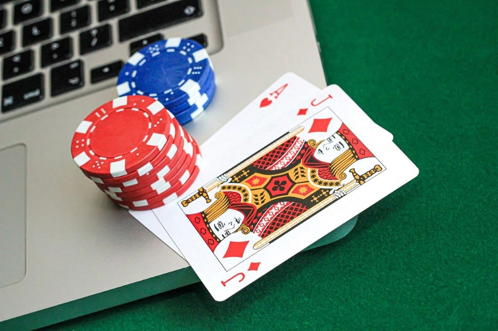 An image showing a strong hand in a game of online poker, chips and a laptop.